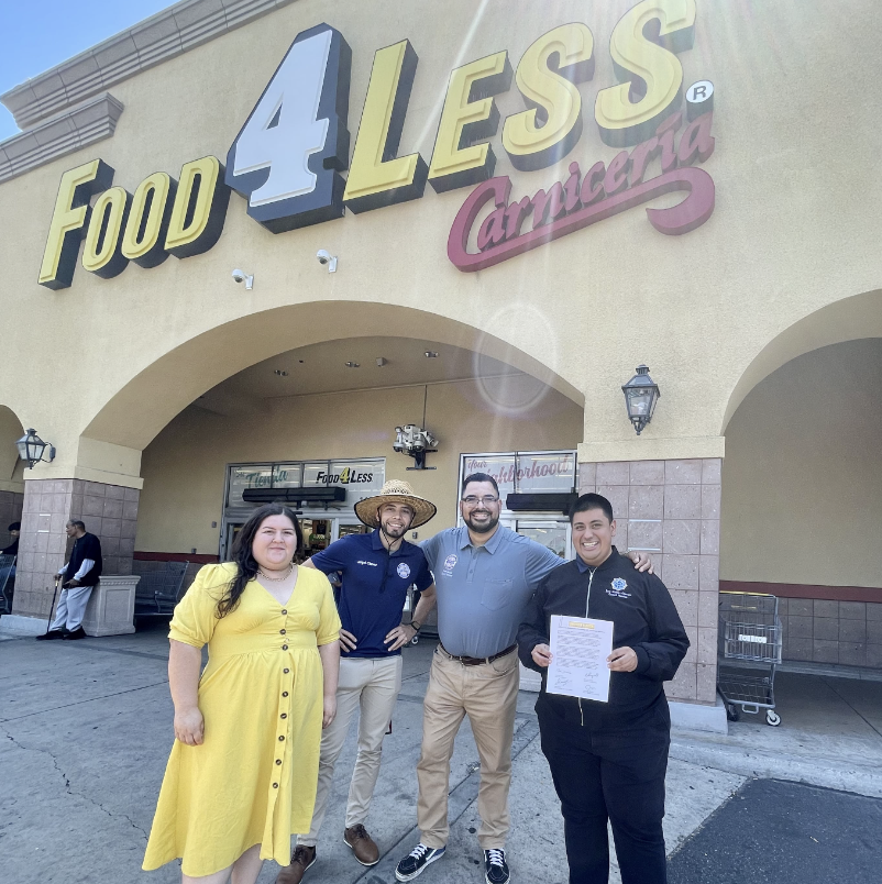 People posing in front of a store with a small sign